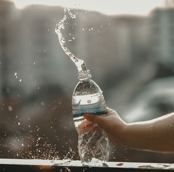 Hand knallt spritzende Wasserflasche auf ein Geländer