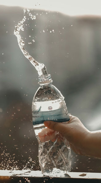 Hand knallt spritzende Wasserflasche auf ein Geländer